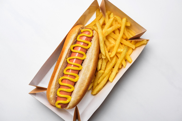 top view of tasty hot dog with fries in cardboard tray on white - Photo, Image