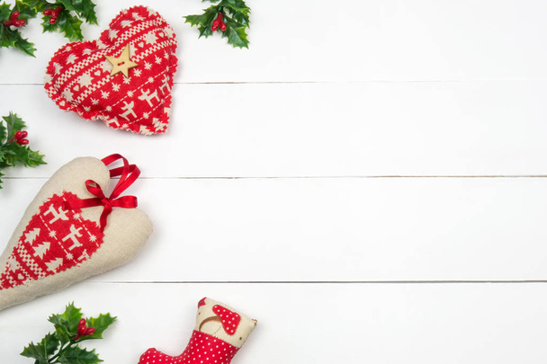 Creative Christmas layout. Red patchwork hearts and mistletoe on white wood background whit copy space. Border arrangement. Flat lay top view.  - Photo, Image