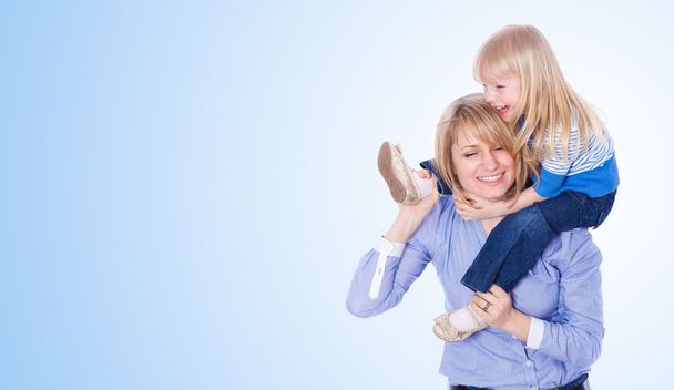 Young mother playing with daughter. On blue background - Photo, image