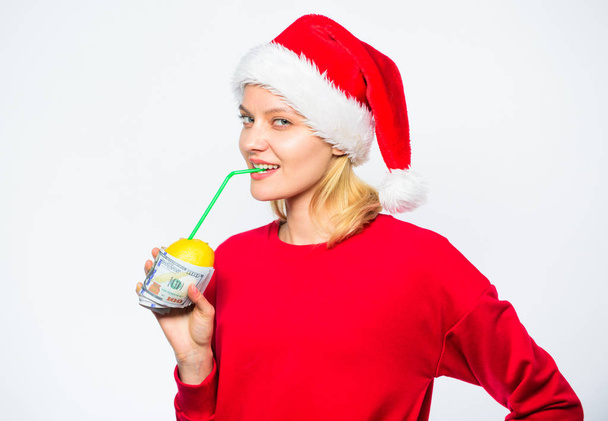 Rich girl with lemon and money. Woman lemon millionaire. Symbol of wealth and prosperity. Source of richness. Richness symbol concept. Girl santa hat drink juice lemon wrapped dollar banknote - Photo, image