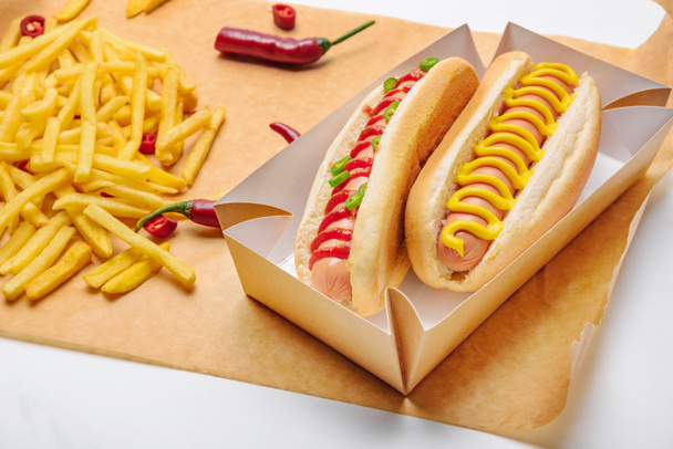 close-up shot of delicious hot dogs with french fries on paper - Photo, Image