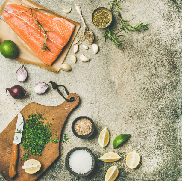 Cooking salted salmon fish. Flat-lay of raw salmon fillet, variety of salts and herbs over grey concrete table background, top view, copy space. Slow or comfort food concept - Photo, image