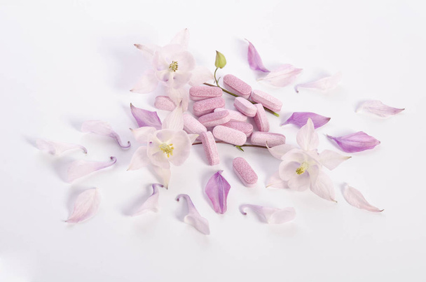 Alternative medicine tablets with flowers and petals on table - Φωτογραφία, εικόνα