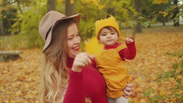 glückliche interrassische Familie. Lässige Mutter und ihr Mischlingsbaby amüsieren sich im Herbstpark. - Filmmaterial, Video