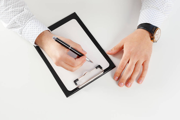 Man holding blank clipboard on white table - Photo, Image
