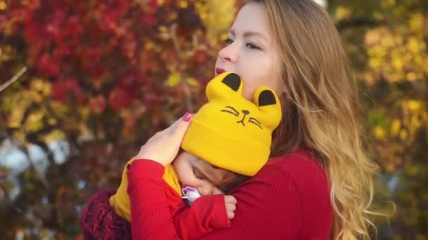 混血家族。母が秋の公園で彼女の腕で眠っている娘を保持します。. - 映像、動画