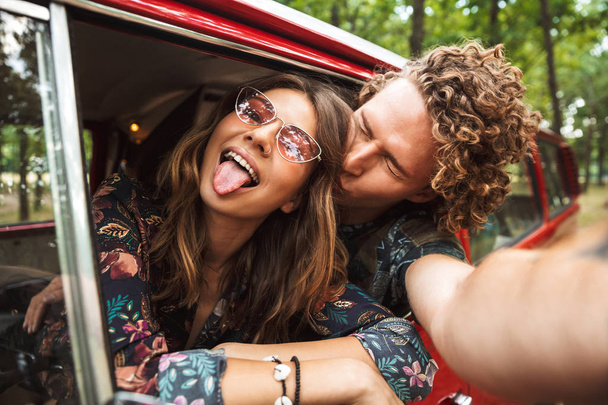 Photo of happy hippie couple smiling, and showing peace sign whi - Fotografie, Obrázek
