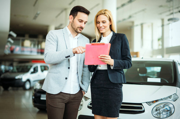 Successful happy businessman in a car dealership - sale of vehicles to customers - Foto, Bild