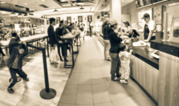 Blurred image customer checkout at Asian bakery shop and waiting in long line behind stanchion barriers. Abstract diverse multiethnic people waiting at bakehouse in America - Photo, Image