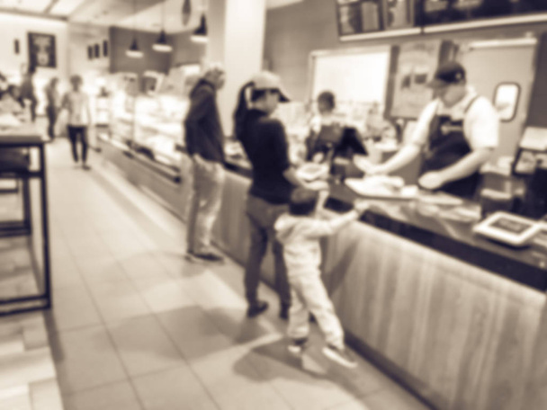 Zamazany obraz klienta kasy w Azji piekarnia sklep i czekanie w długiej kolejce za słupek bariery. Streszczenie różnorodnych wieloetnicznym osób czeka w bakehouse w Ameryce - Zdjęcie, obraz