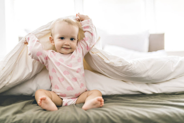 Adorable baby girl cover with white sheet wearing pink clothes - Foto, Imagem