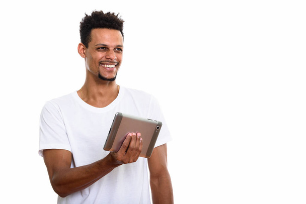 nachdenklicher junger glücklicher afrikanischer Mann lächelt, während er digitale - Foto, Bild