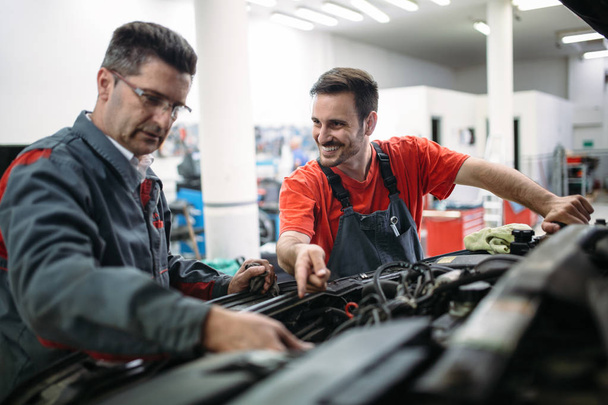 Car mechanics working at automotive service center together - Foto, immagini