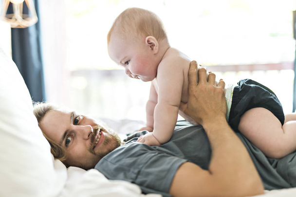 A father playing with adorable baby girl in bedroom - Photo, image