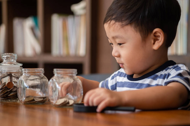 cute boy putting money coins in glass,saving money concept - Photo, image