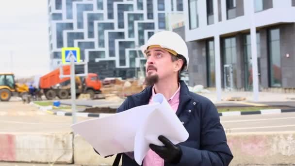 construction engineer or architect in helmet with a construction plan on the construction site. - Imágenes, Vídeo