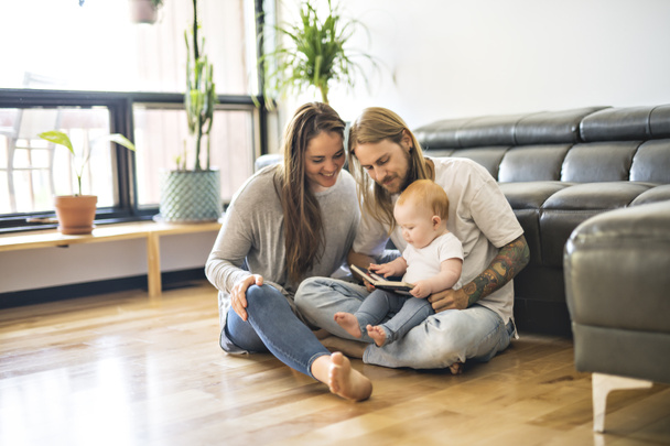 Familie mit Baby und Buch im Wohnzimmer - Foto, Bild