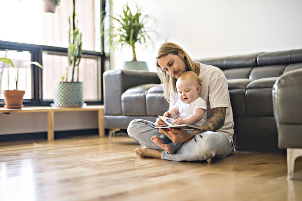 father with her baby and a book in the living room - Foto, imagen