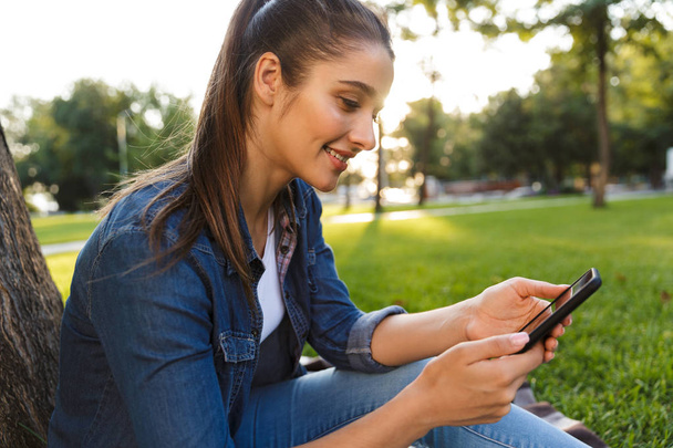 Image of amazing beautiful young woman student in the park using mobile phone. - 写真・画像