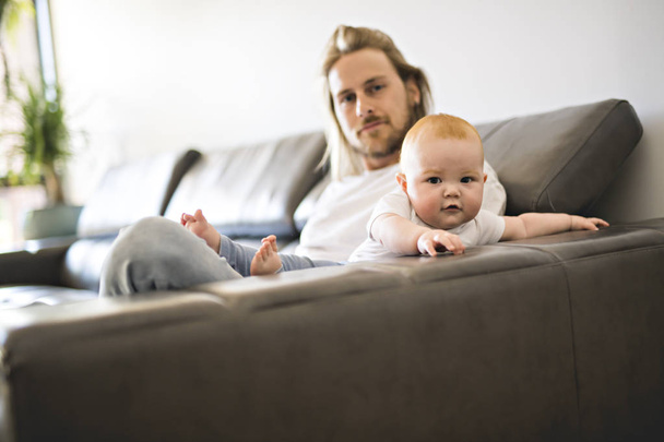 father playing with baby daughter on sofa at home - Фото, зображення