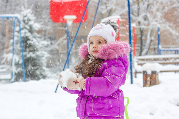 Pieni lapsi tyttö pelaa lumipalloja talviaamuna
 - Valokuva, kuva