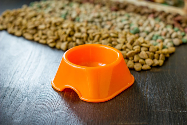 Kleine oranje schaal voor voeder voor gezelschapsdieren en droog voedsel als achtergrond - Foto, afbeelding