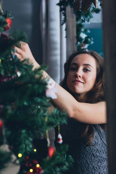 Beautiful girl arranges christmas tree - christmas and new year concept. - Zdjęcie, obraz