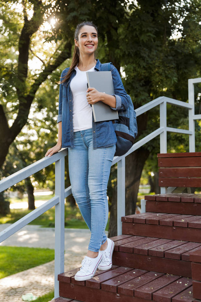 Image of pretty young caucasian woman standing outdoors holding laptop computer. - Photo, Image