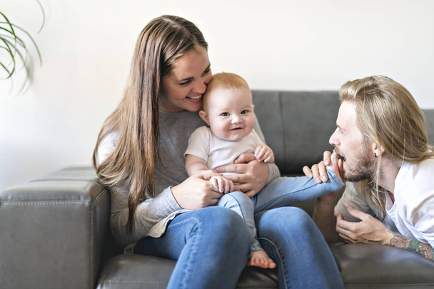 parent with baby daughter on sofa at home - Valokuva, kuva