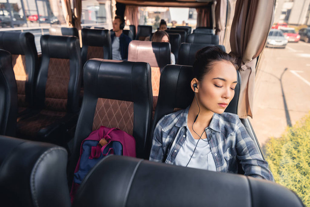 asian young woman sleeping and listening music in earphones during trip on travel bus  - Foto, immagini