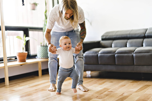 Father help Baby Daughter Take First Steps At Home - Valokuva, kuva