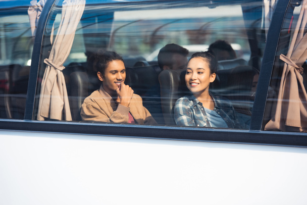 fröhliches multikulturelles Touristenpaar während einer Busfahrt  - Foto, Bild