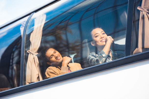 счастливые азиатские и смешанные туристы расы во время поездки на туристическом автобусе
 - Фото, изображение