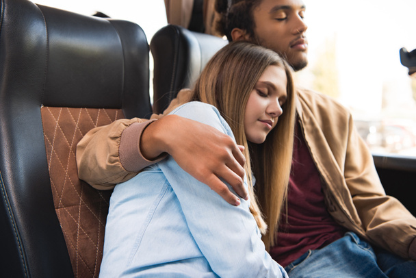 молодая мультикультурная пара туристов спит во время поездки на туристическом автобусе
 - Фото, изображение
