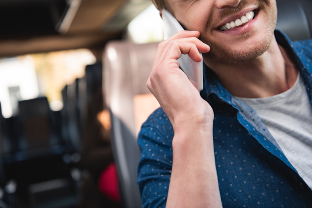 partial view of smiling man talking on smartphone during trip on travel bus - Foto, Bild
