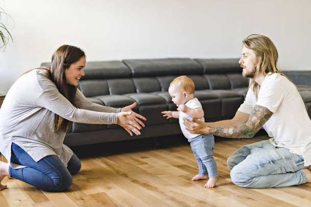 Parent help Baby Daughter Take First Steps At Home - Foto, Imagen