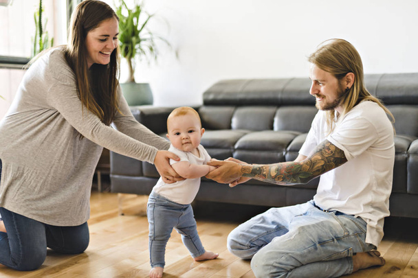 Parent help Baby Daughter Take First Steps At Home - Valokuva, kuva