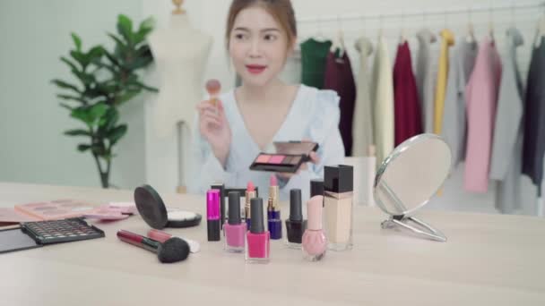 Beauty blogger present beauty cosmetics sitting in front camera for recording video. Beautiful asian woman use cosmetics while review make up tutorial broadcast live video to social network by internet. - Footage, Video
