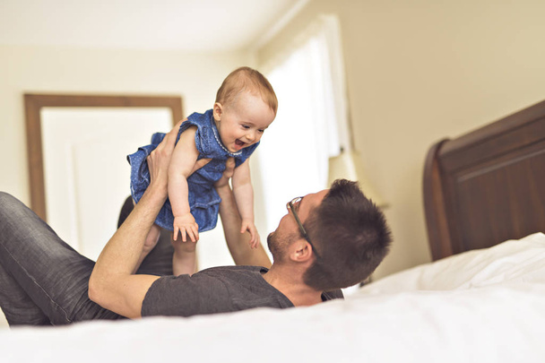 Father playing with her baby in the bedroom - Фото, изображение