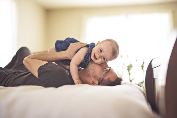 Father playing with her baby in the bedroom - Foto, Imagem