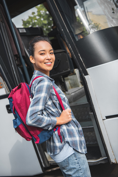  asian woman with backpack posing near travel bus at street - Foto, Imagen
