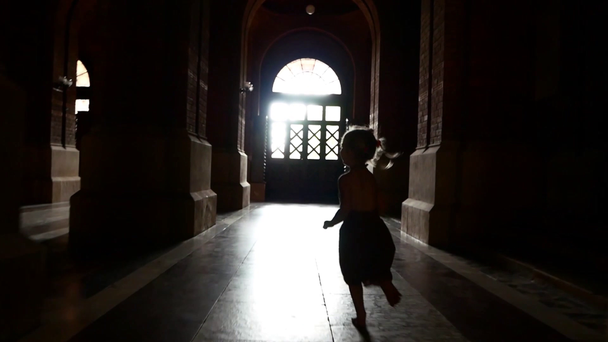 Una niña con un vestido corre por el oscuro corredor entre las columnas. Jugando a ponerse al día
. - Metraje, vídeo