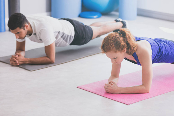 Girl and boy doing plank on a gym - Фото, зображення
