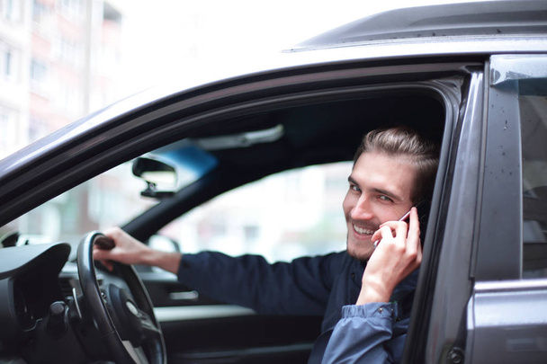 крупним планом. усміхнений чоловік розмовляє на мобільному телефоні в машині
. - Фото, зображення