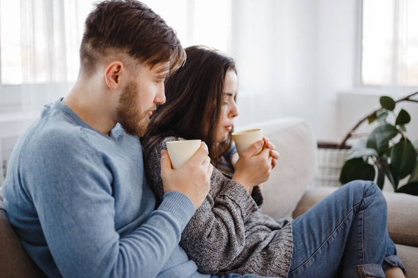 Young couple relaxing at home with hot drinks - Valokuva, kuva