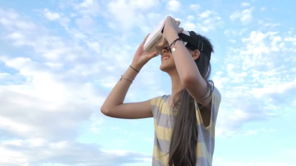 Zwolnionym tempie 4k Asian Girl zabawy z okulary wirtualnej rzeczywistości, stojąc nad niebo - Materiał filmowy, wideo