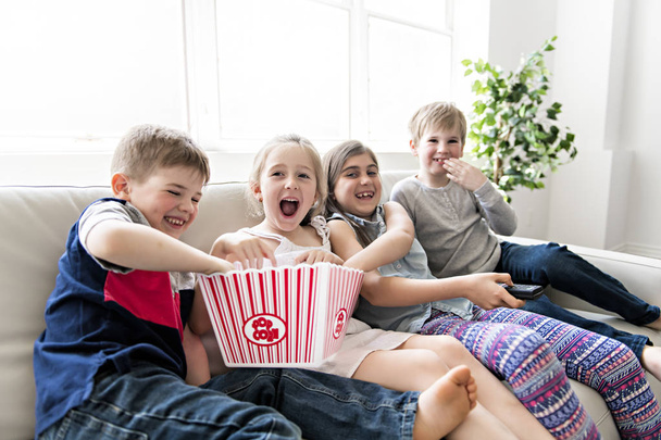 child group eating popcorn together on sofa - Foto, immagini