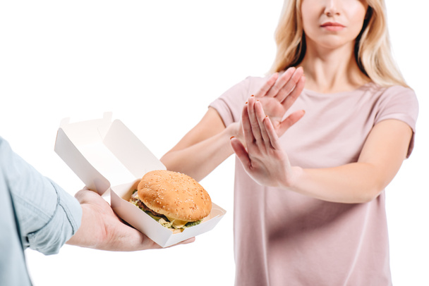 imagen recortada de la mujer rechazando hamburguesa malsana aislada en blanco
 - Foto, Imagen