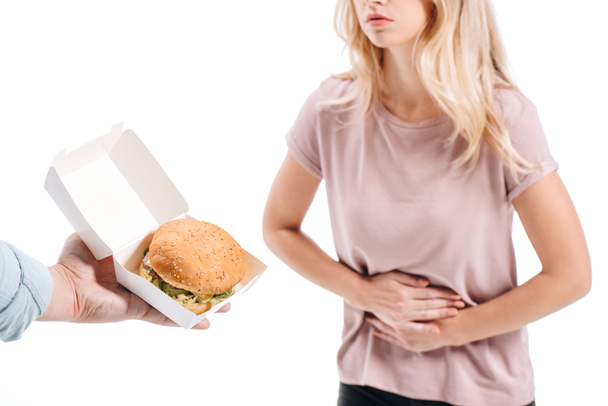 cropped image of woman showing stomach pain, man proposing burger isolated on white - Photo, image