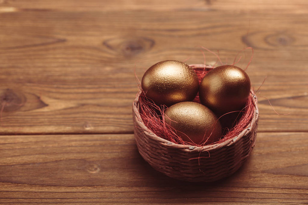 gold easter eggs on wooden table - Fotoğraf, Görsel